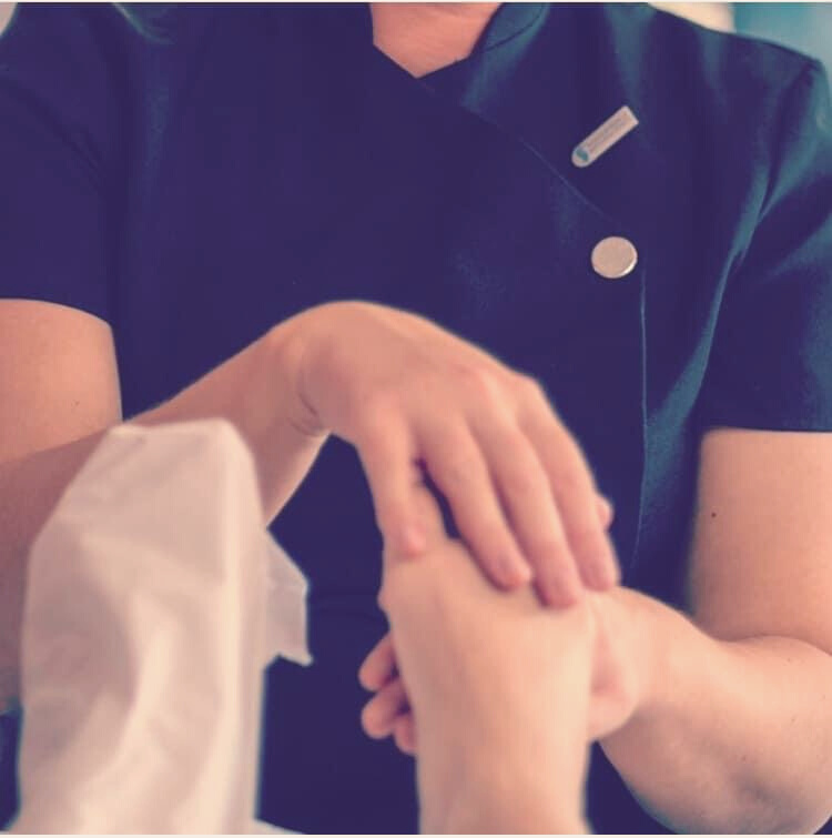A reflexologist carrying out a reflexology treatment on her client’s feet 